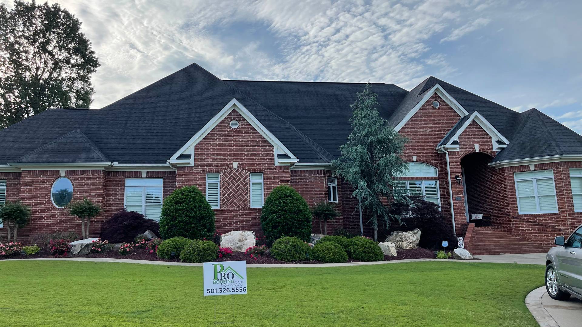 Brick home in Benton AR with a new dark shingle roof and a clean front lawn