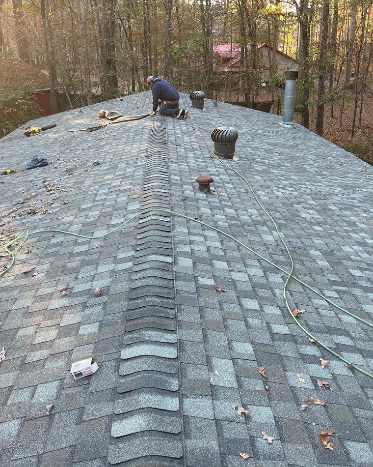 Pro Roofing crew member installing shingles along a roof ridge in Benton AR