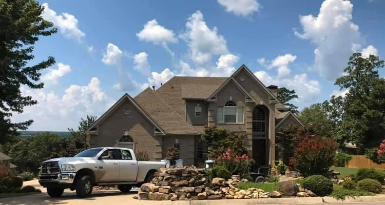 Two-story stone home with a new shingle roof in central Arkansas